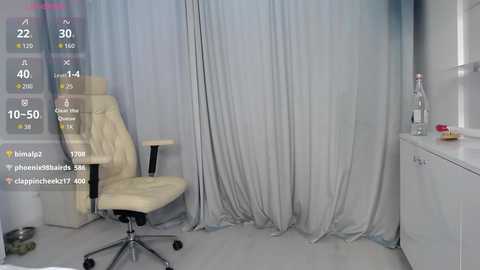 Video of a minimalist, modern room with a white leather office chair, beige curtains, and a glass water bottle on a white counter.