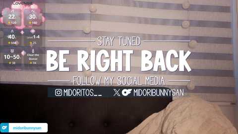 A video of a bedroom with a striped, light-colored bedspread, a digital clock on the wall, and a pillow visible. Text on the screen reads: \"Stay tuned BE RIGHT BACK Follow my social media.\