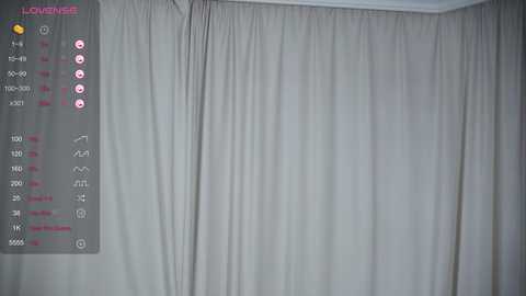 Video of a modern, minimalist bedroom with a large, light gray, pleated curtain covering a window. The left side features a digital display with room temperature and humidity readings.