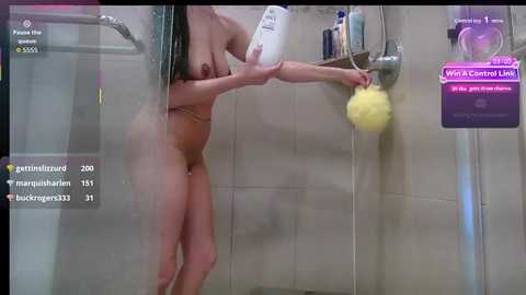 Video of a naked woman with fair skin and long black hair, shampooing in a modern, beige-tiled bathroom. She holds a large bottle of shampoo and a yellow loofah.