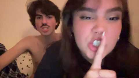 Media: Video of a young man with mustache, shirtless, and a woman with long hair and a nose ring, both smiling and making a peace sign.