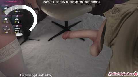 A video featuring a man's erect penis on a white towel, with a woman's white lace thigh-high stockings and a man's beige jacket in the background. The image includes a digital overlay with a 50% off discount.