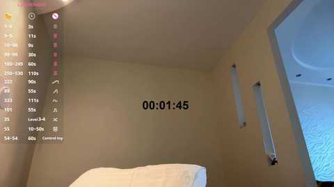 Video of a minimalist, empty bedroom with beige walls, a small window, and a digital camera display showing \"00:01:45\" in the top left corner.