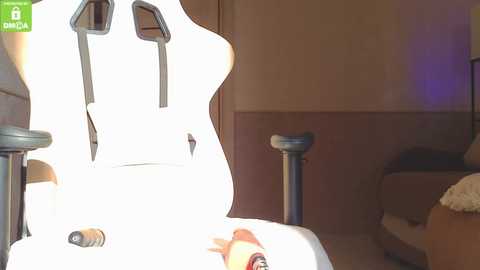 Video of a white electric guitar with a pickguard and black pickups, leaning against a beige wall with a green logo on the top left.