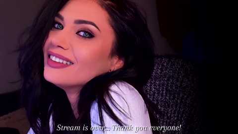 Video of a smiling woman with long, dark hair, wearing a white shirt, sitting in a dimly-lit room. Text at the bottom reads, \"Stream is open. Thank you everyone!\