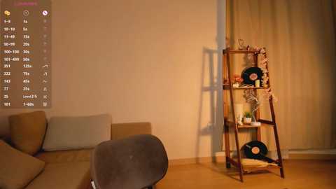 Media: Video of a warmly lit, minimalist living room with beige walls, a brown L-shaped sofa, a wooden ladder shelf, and a grey chair.