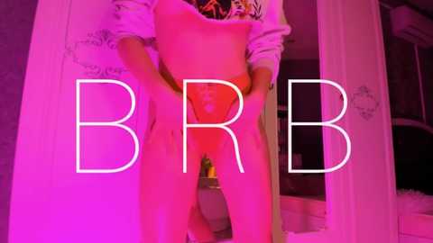 Video of a nude person, possibly male, with \"BBR\" text overlay, positioned against a pink-lit background, showcasing intimate details.