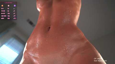 A video of a wet, glistening, female torso with visible nipples, taken from a low angle, showing the skin's texture and contours.