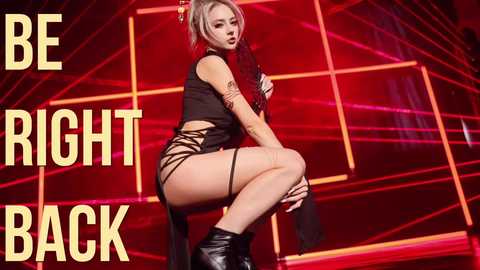 Media: Video of a confident, tattooed woman in a black crop top and shorts, straddling a chair against a vibrant red grid backdrop. \"BE RIGHT BACK\" is written in bold yellow letters.