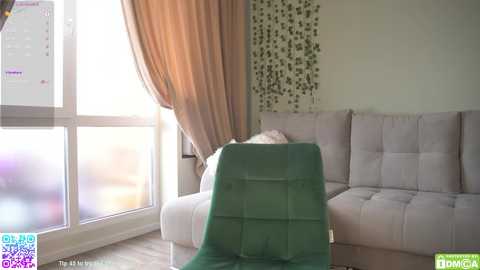 Media: Video of a modern living room with beige sofa, green chair, sheer beige curtains, and a wall with green leaf pattern.
