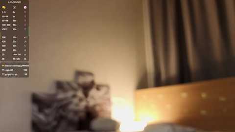 A blurred video of a dimly lit bedroom with a bed, a wooden nightstand, and a lamp emitting a warm glow.