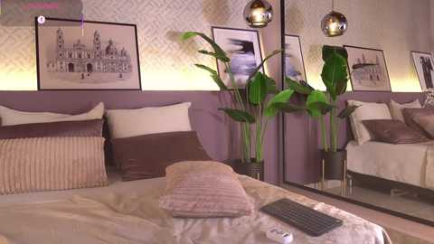 Video of a modern bedroom with beige walls, a large bed, brown pillows, potted plants, framed art, and hanging spherical pendant lights.