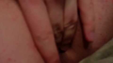 Video of a close-up of a woman's hand spreading her labia, revealing her vulva. The background is blurred, focusing on the intimate details of her genital area.