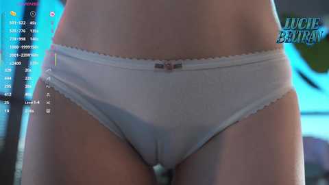 A close-up video of a woman's lower torso wearing white lace-trimmed panties, with a digital overlay displaying a \"Juicy Buns\" game interface.