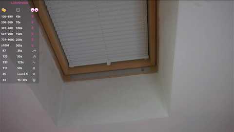 Media: Video of a white ceiling with a wooden-framed, partially open white blind, showing a view of a room below.