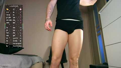 Video of a person in black shorts, standing in a bedroom with a TV showing a digital clock and calendar. The room features a bed, dresser, and window.