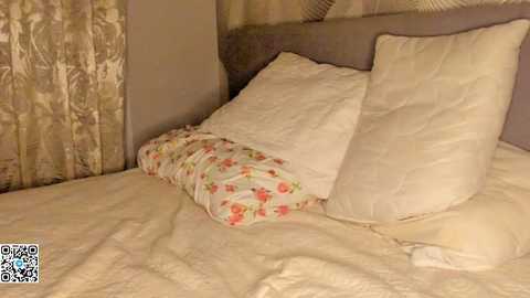 Video of a cozy bedroom with a beige headboard, a floral-patterned pillow, and a white pillow, against a muted brown and beige background.