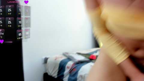 A blurred, sexually explicit video features a woman in a yellow top, partially undressed, standing in a bedroom with a bed and calendar in the background.