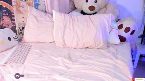 Video of a cozy bedroom with a white bed, plush pillows, a teddy bear, and a laptop on the bed, lit by soft purple light, creating a warm, inviting atmosphere.