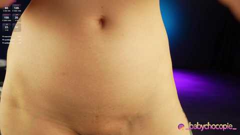 Video of a close-up, light-skinned, nude torso with a small belly button, set against a blurred, dark background. The image features a watermark \"@babychocolate\" in pink text at the bottom right.