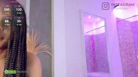 Video of a woman with braided hair, partially visible, standing in a modern bathroom with purple lighting and a tiled shower.