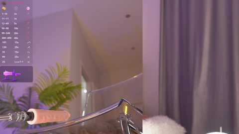 A video of a modern bathroom with a sleek, chrome faucet, a potted fern, and purple curtains in the background, displaying a minimalist, contemporary design.