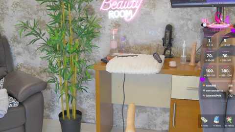 Video of a modern, cozy living room with a gray couch, a tall bamboo plant, a wooden desk with a massage chair, and a neon sign reading \"Beauti\" on a textured gray wall.