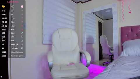 Video of a modern bedroom with a white leather recliner, a bed, and a desk chair under a pink LED light.