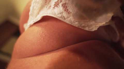 A close-up video of a woman's bare back, showing a large, smooth, and slightly rounded area. The skin is tan, and a white lace bra is partially visible, indicating a feminine body. The background is blurred, focusing on the texture and curves of the skin.