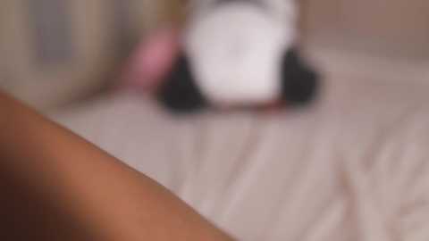 A blurred video shows a person in pink and black clothing, lying on a beige bedspread, with the focus on their upper body.