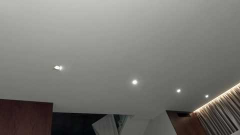 Video of an indoor ceiling with recessed lighting, showcasing a minimalist, modern design with smooth, white surfaces and a subtle lighting effect.